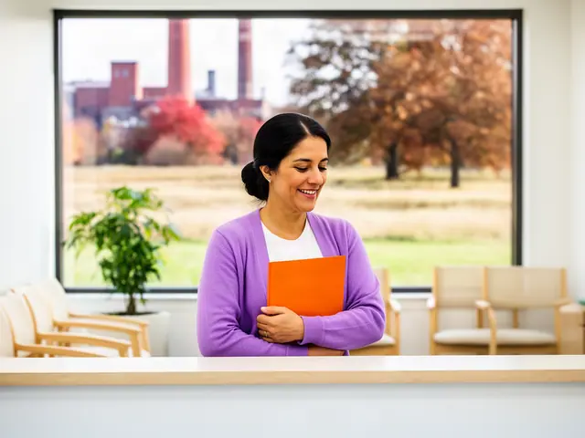 A clinic office manager holding a folder behind a reception counter.